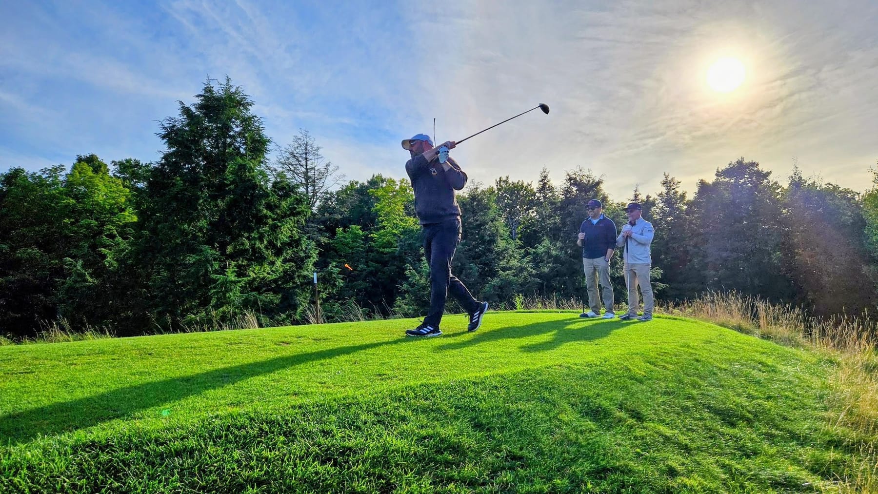 A King swinging on an elevated tee at sunset