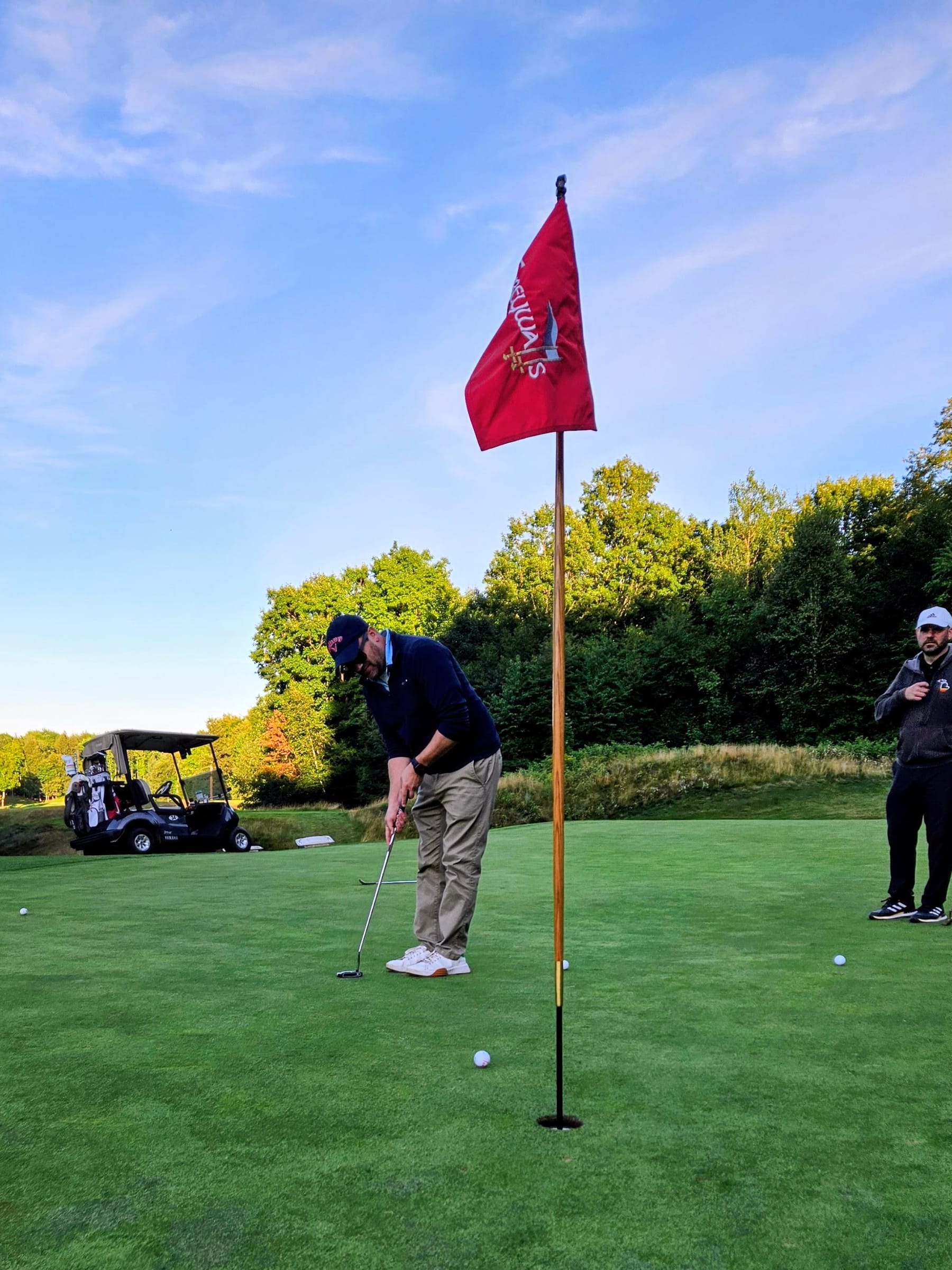 A King putting at a red flag at dusk